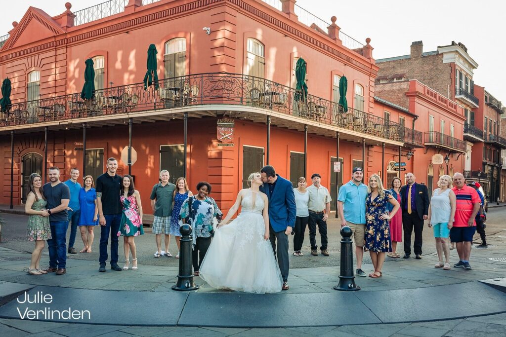 bride and groom kissing in the French Quarter surrounded by their family members