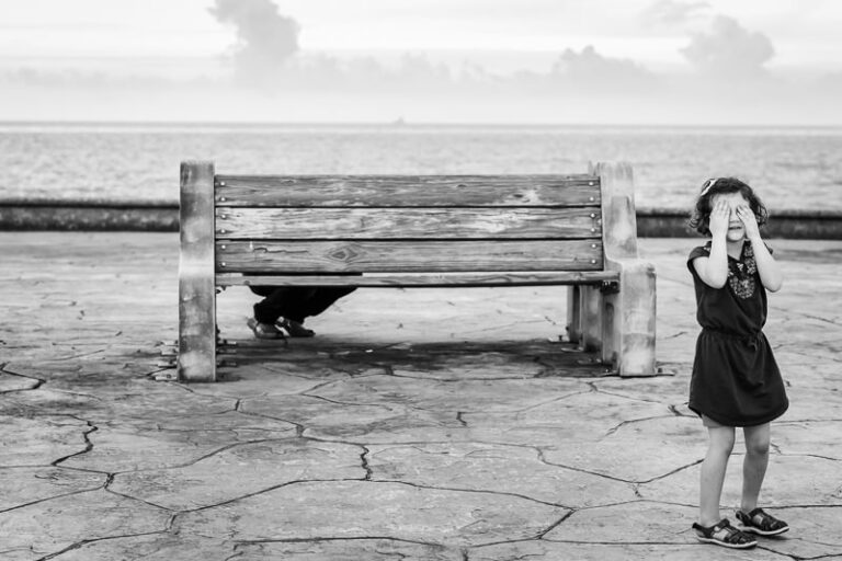 young girl playing hide and seek by the lake