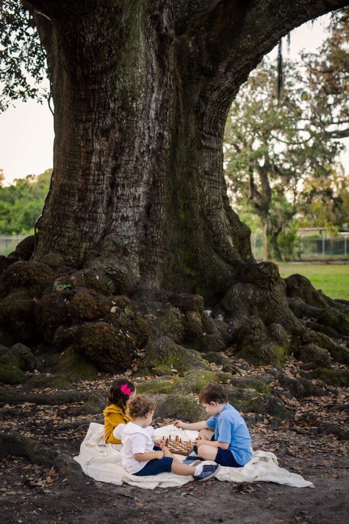 three kids playing chess by the Tree of Life