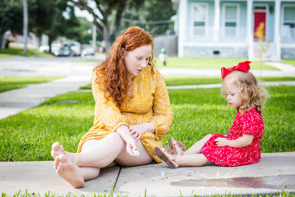 mother and child sitting on the sidewalk