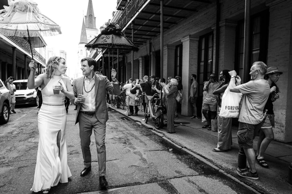 Bride and groom walking in a street with umbrellas on hand