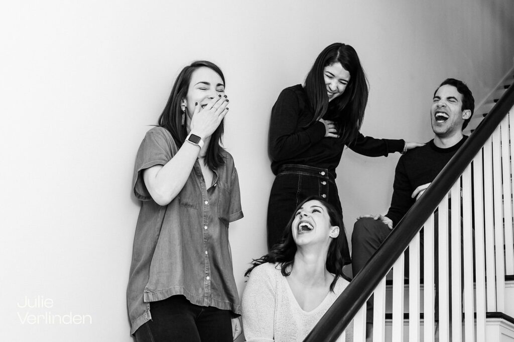four young adult siblings on staircase laughing hard