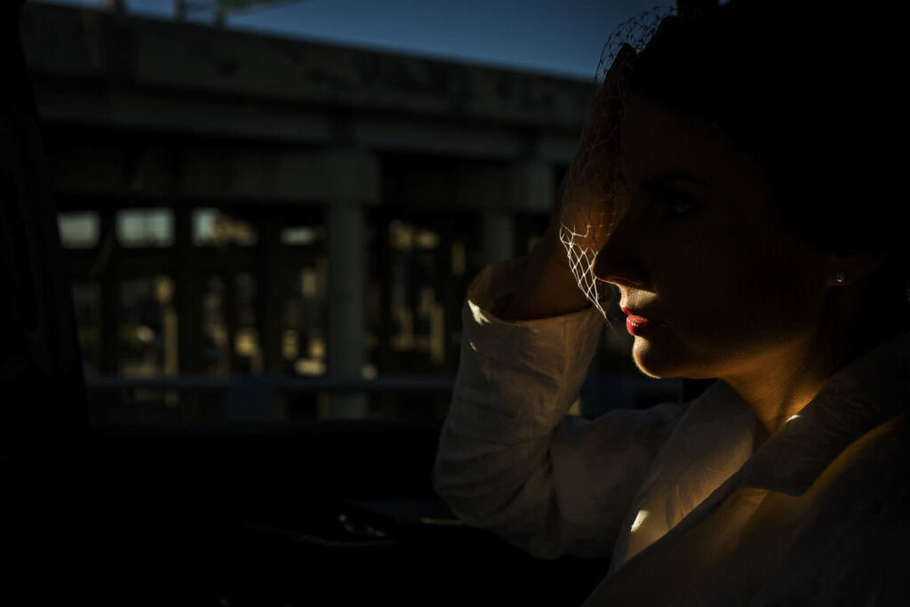 bride sitting in car with only red lipstick lit up by the sun